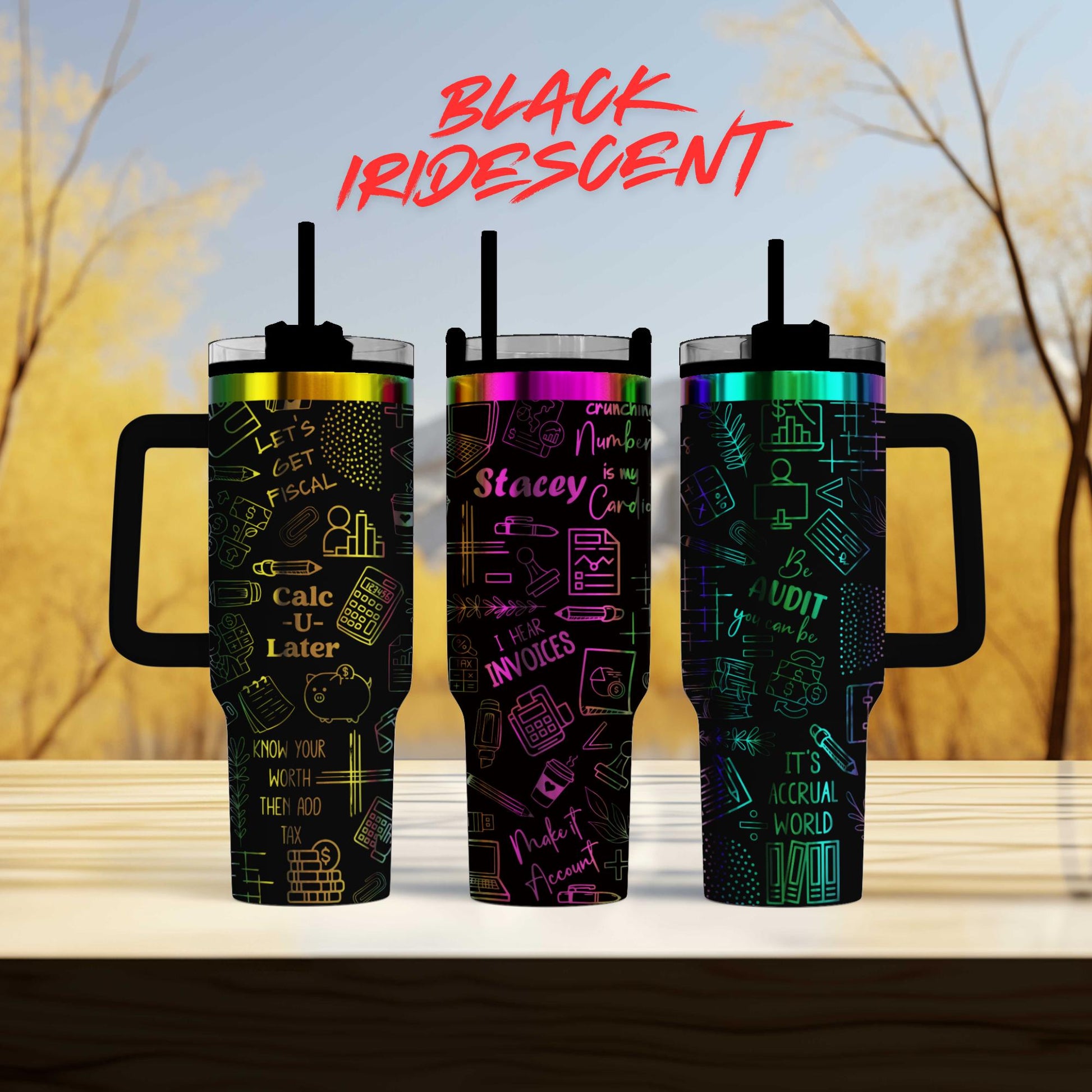 three colorful tumblers with various text and graphics printed on them, set against a blurred background of trees.