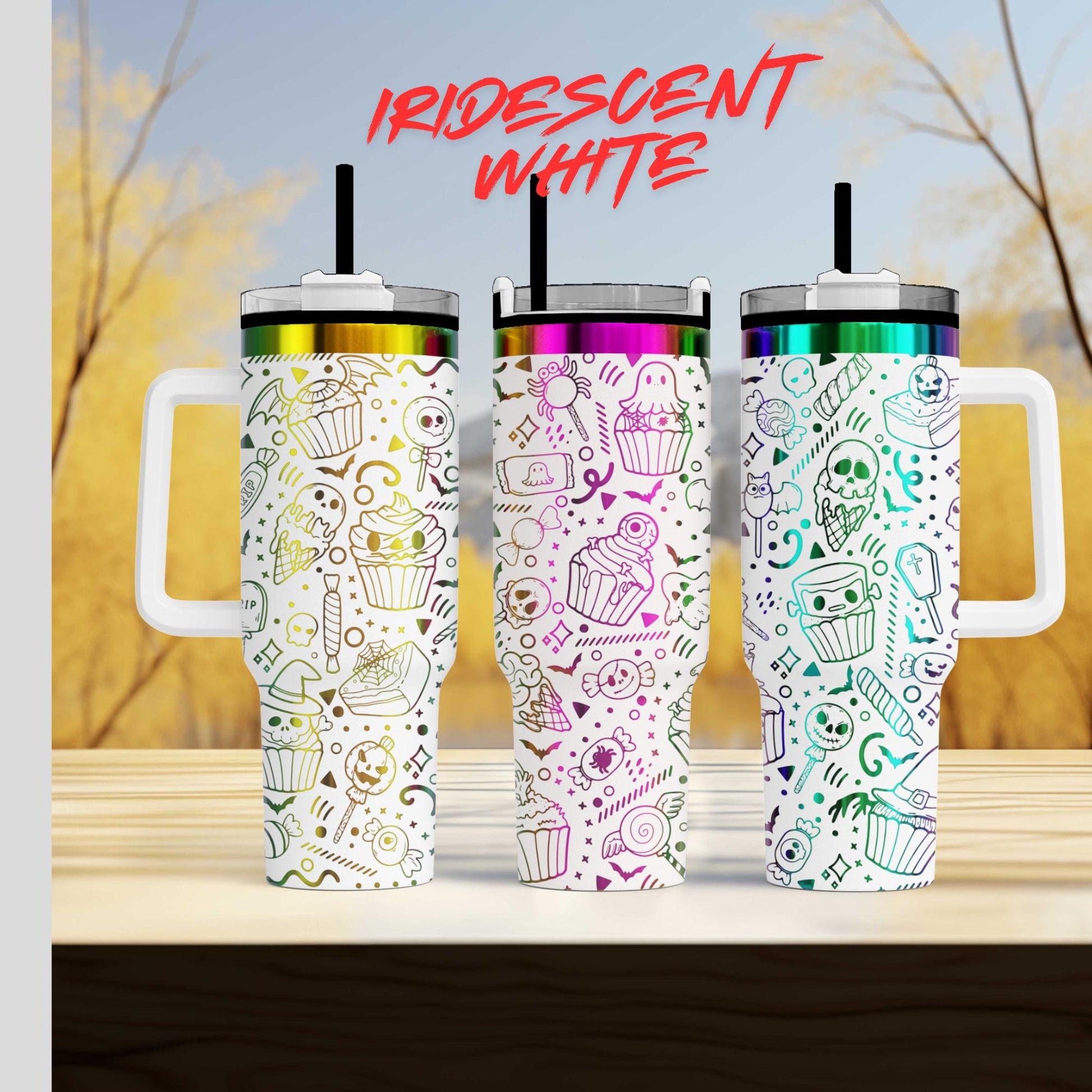 Three colorful tumblers with various designs and patterns, including skulls, cupcakes, and other festive elements, are displayed on a wooden surface against a blurred background.