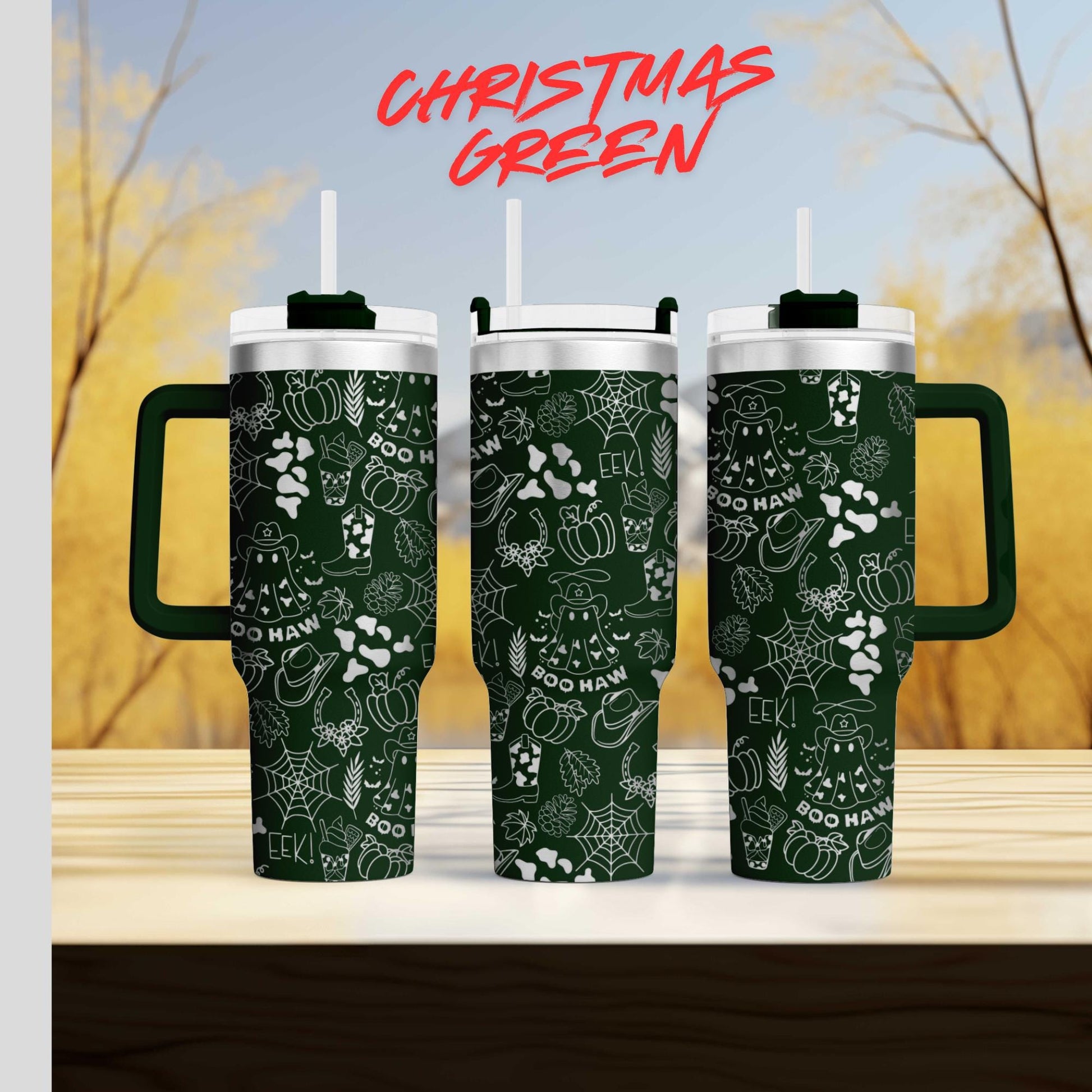 three green tumblers with white designs, including various Halloween-themed elements such as bats, pumpkins, and spiders, against a blurred background of trees and a blue sky.