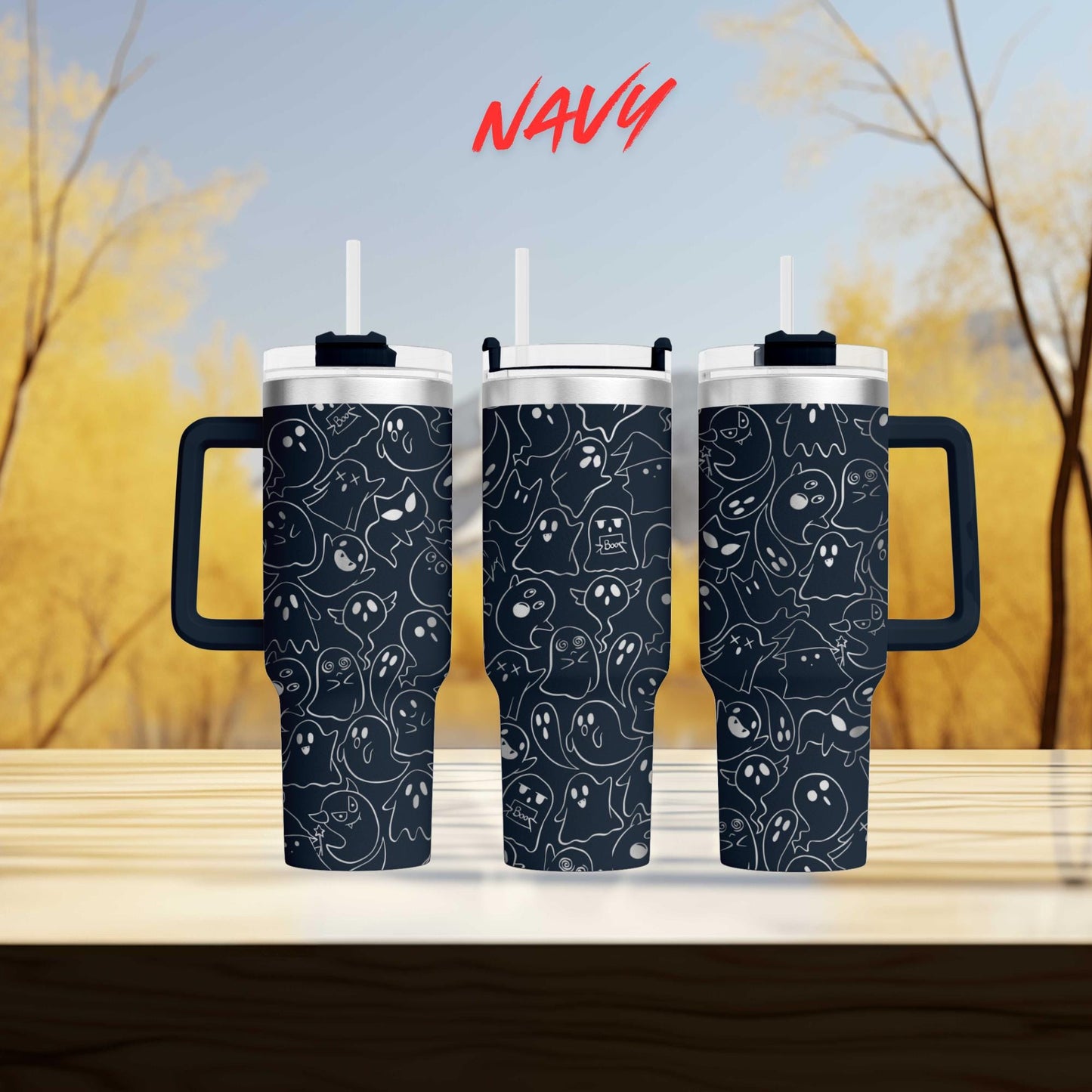 three black tumblers with a black and white ghost pattern design, placed on a wooden surface against a blurred background of trees.
