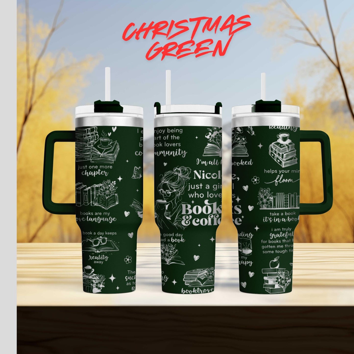 three green tumblers with white text and illustrations on them, set against a blurred background of trees and a blue sky.