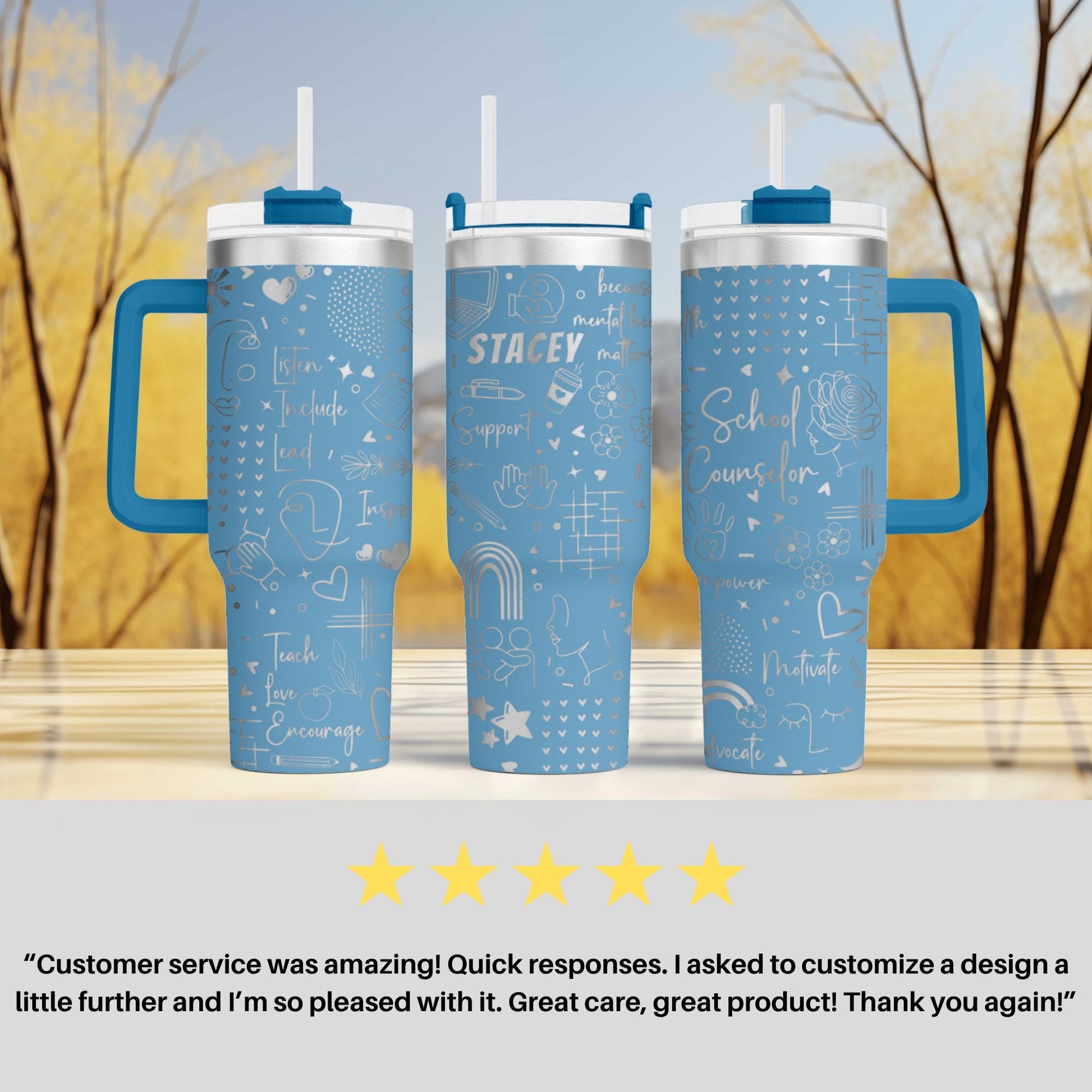 three blue tumblers with white text and designs, placed on a wooden surface against a blurred background of trees.