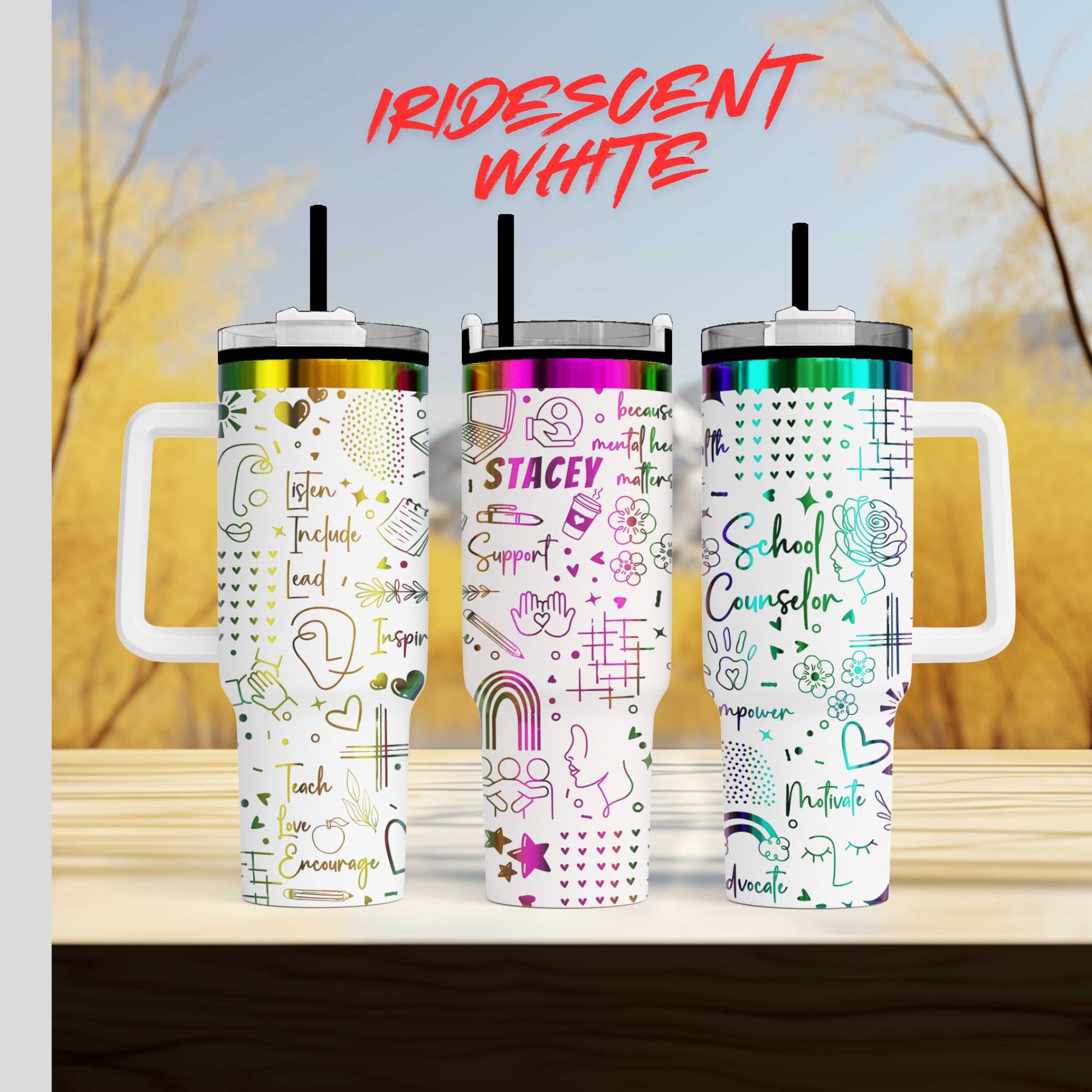 Three colorful tumblers with various designs and text printed on them, placed on a wooden surface against a blurred background.