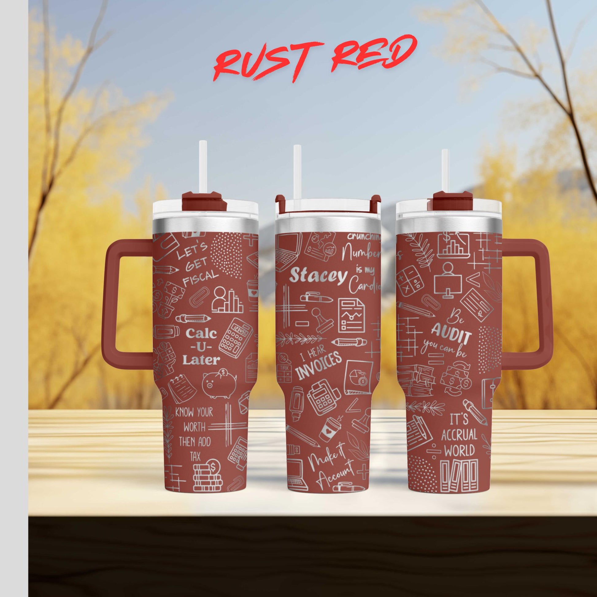 Three red tumblers with white text and graphics printed on them, placed on a wooden surface against a blurred background of trees.