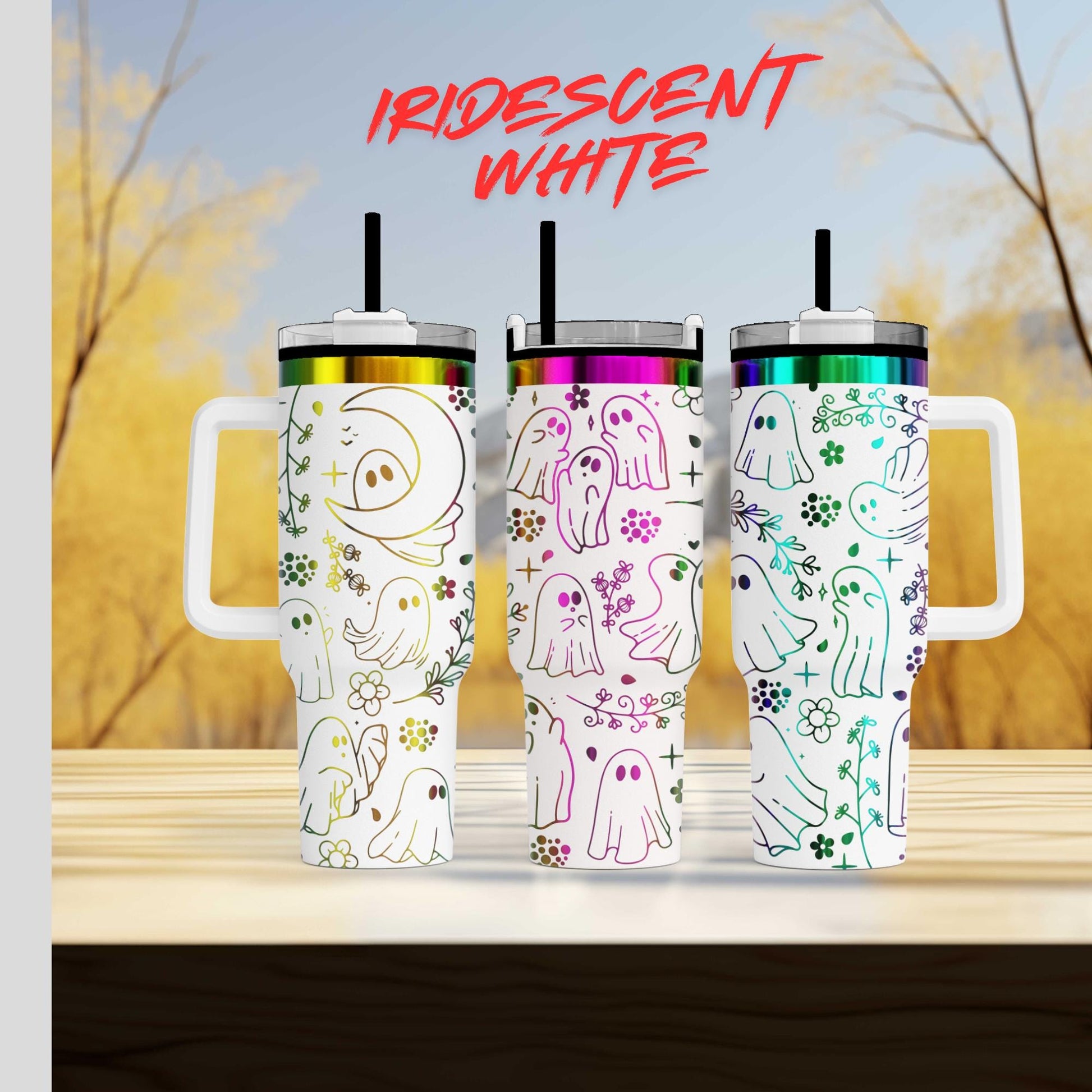 Three colorful tumblers with ghost designs on them, set against a blurred background of trees and sky.