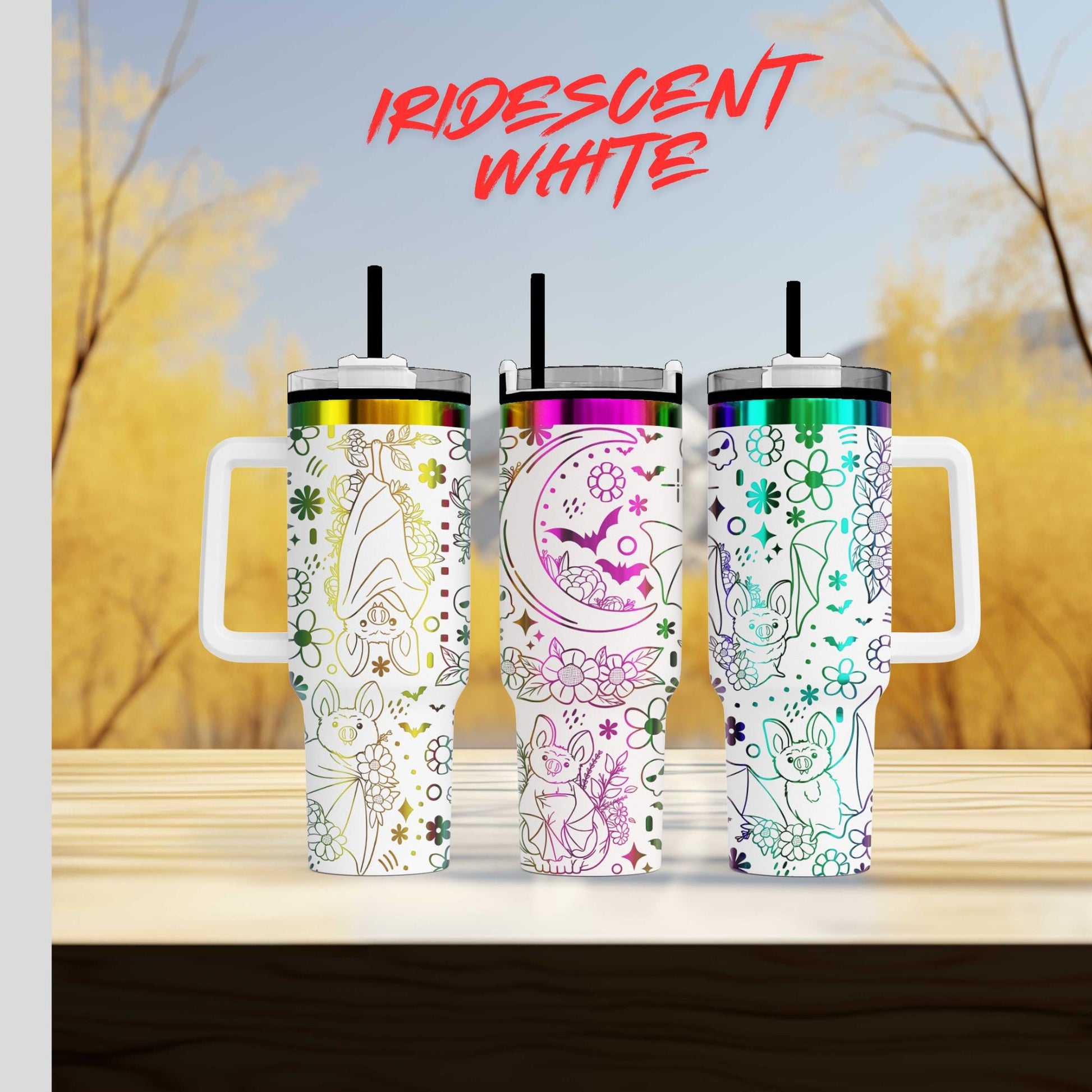 Three colorful, patterned tumblers with handles, arranged on a wooden surface against a blurred background of trees.