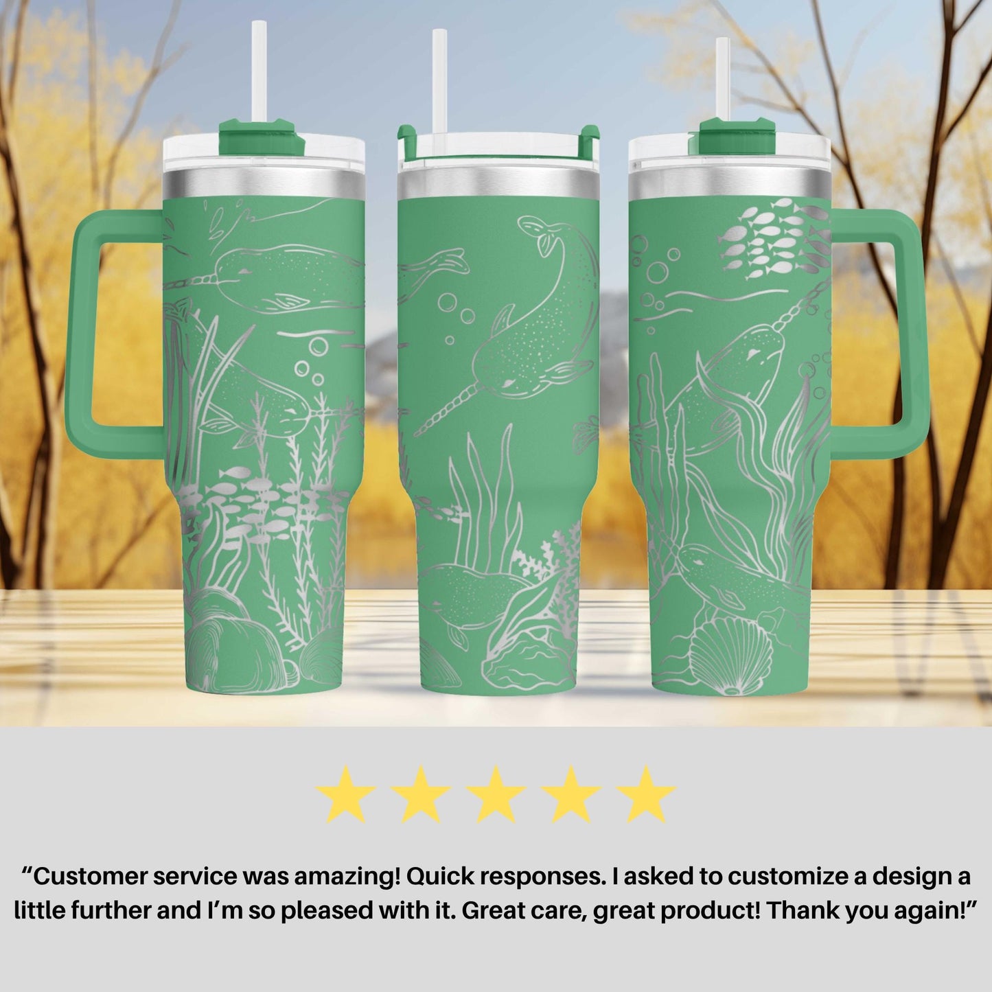 three green tumblers with white designs, including fish and seaweed, placed on a wooden surface against a blurred background of trees.