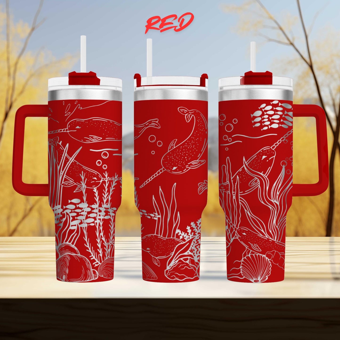 three red tumblers with white designs depicting marine life, including fish, plants, and bubbles, against a blurred background of trees.