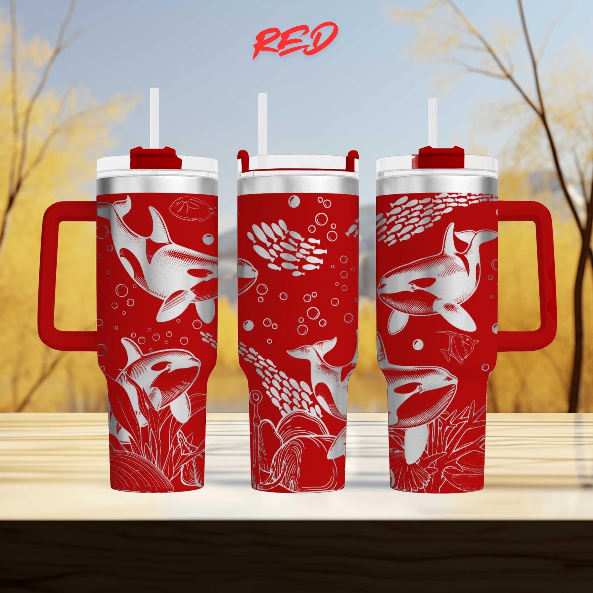three red and white tumblers with fish designs, including a whale and bubbles, against a blurred background of trees.