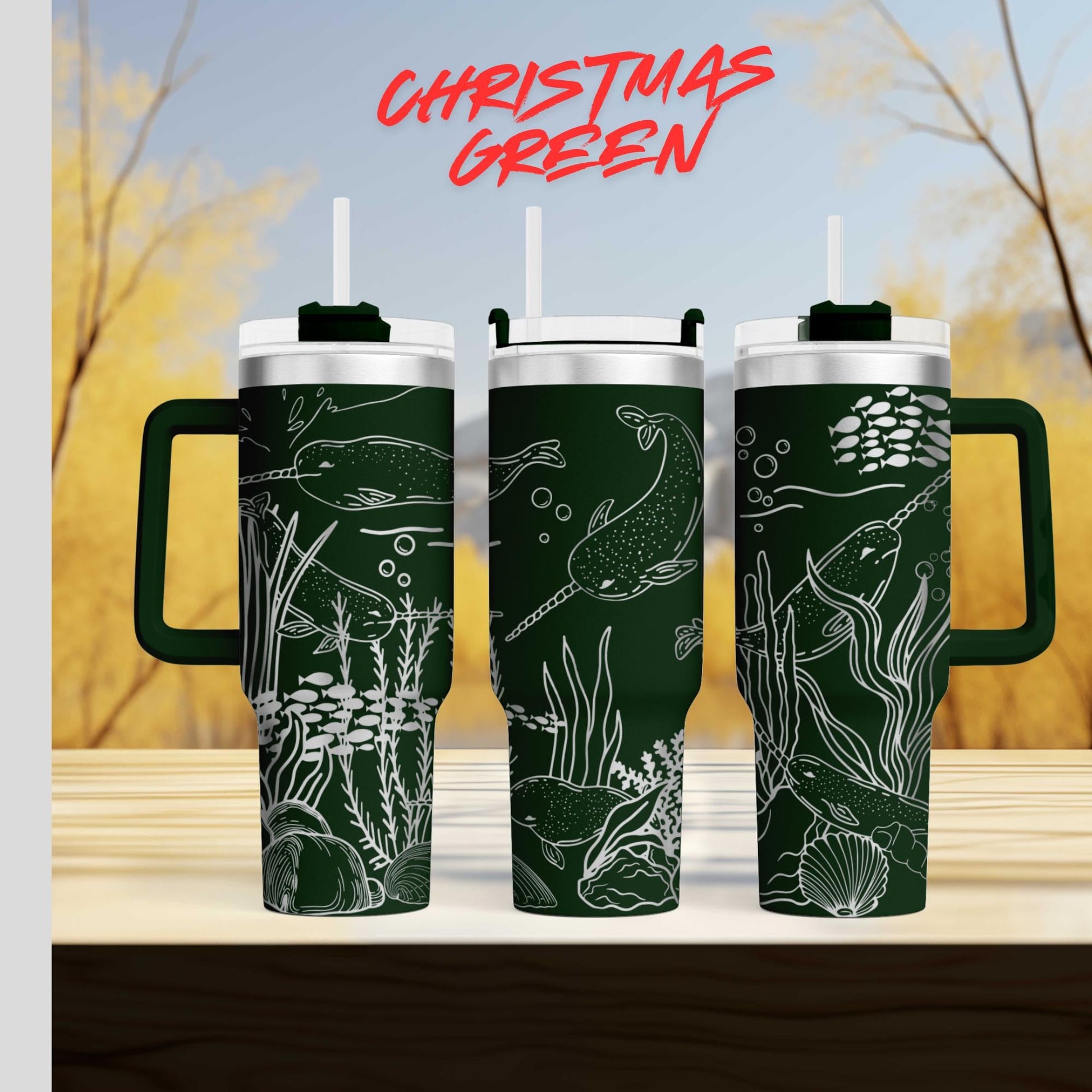 three green tumblers with white designs depicting marine life, such as fish and seaweed, against a blurred background of trees and sky.