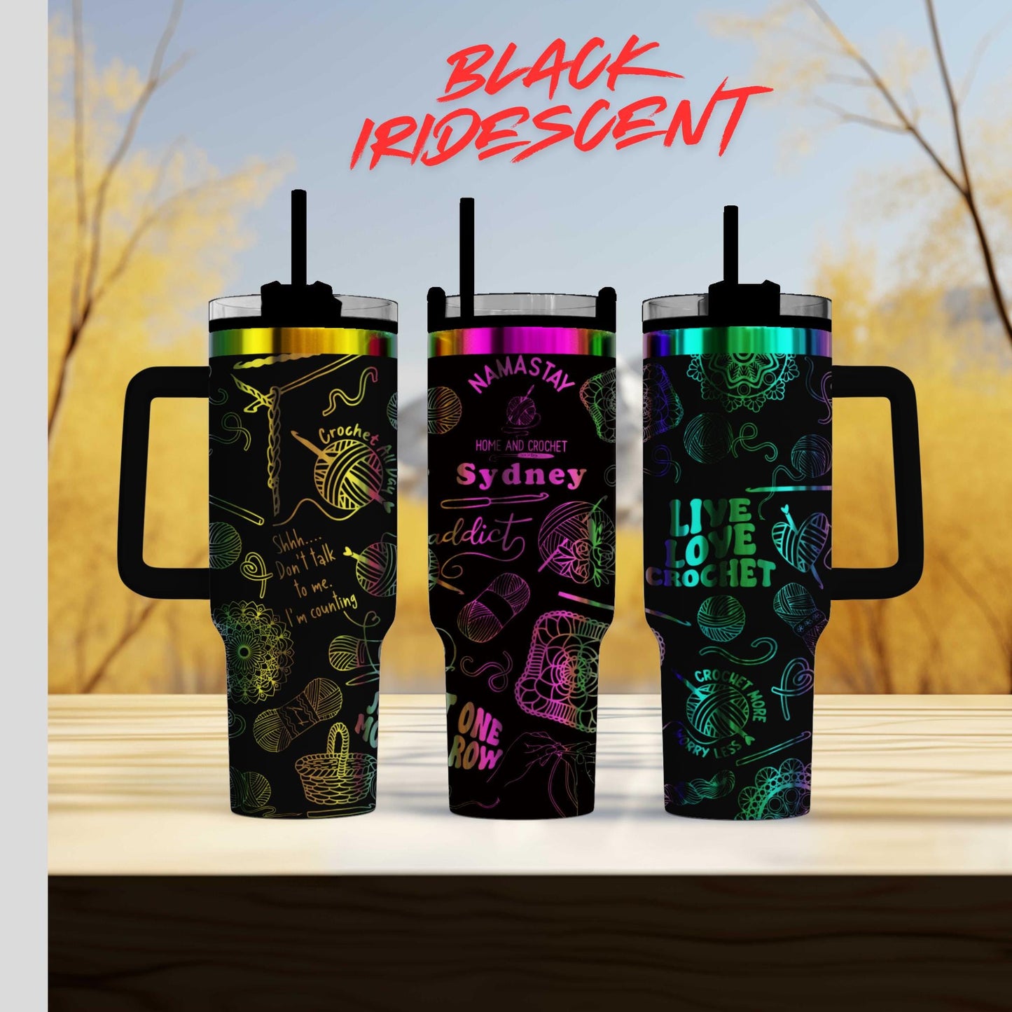 Three colorful tumblers with various designs and text on them, placed on a wooden surface against a blurred background.