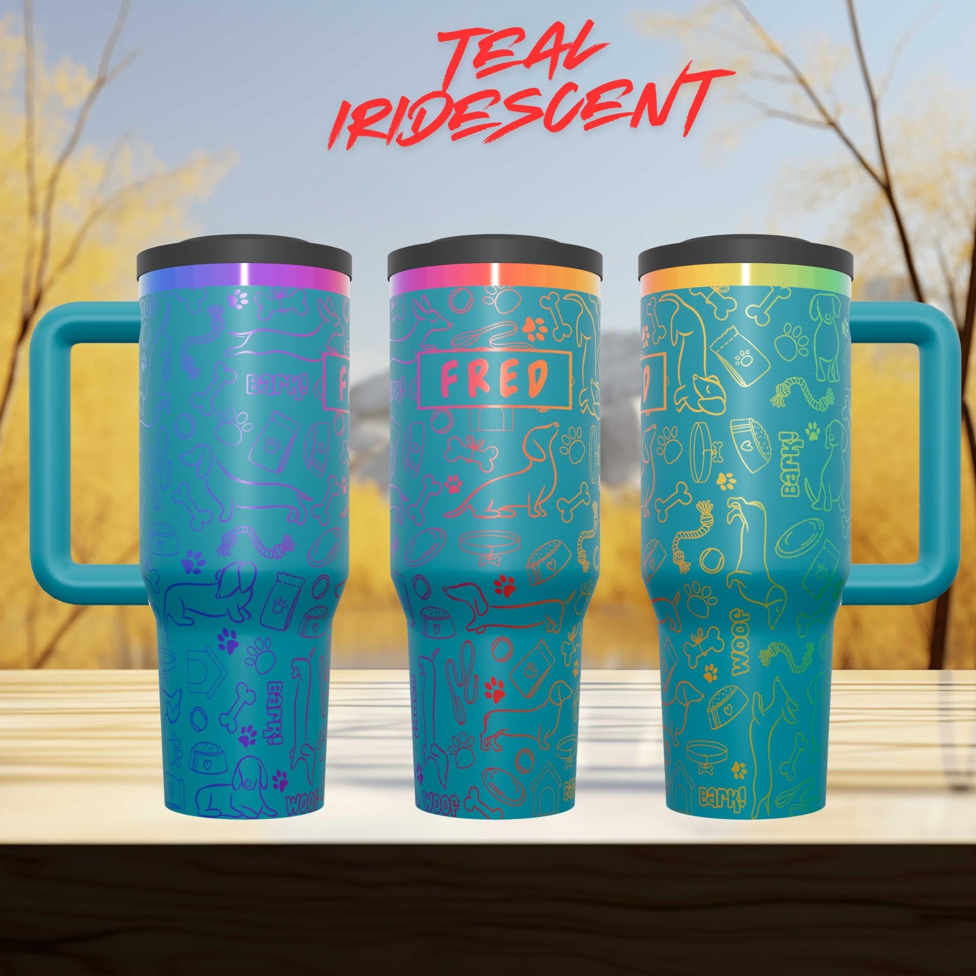 three colorful teal-colored mugs with various designs and text on them, placed on a wooden surface against a blurred background of trees.