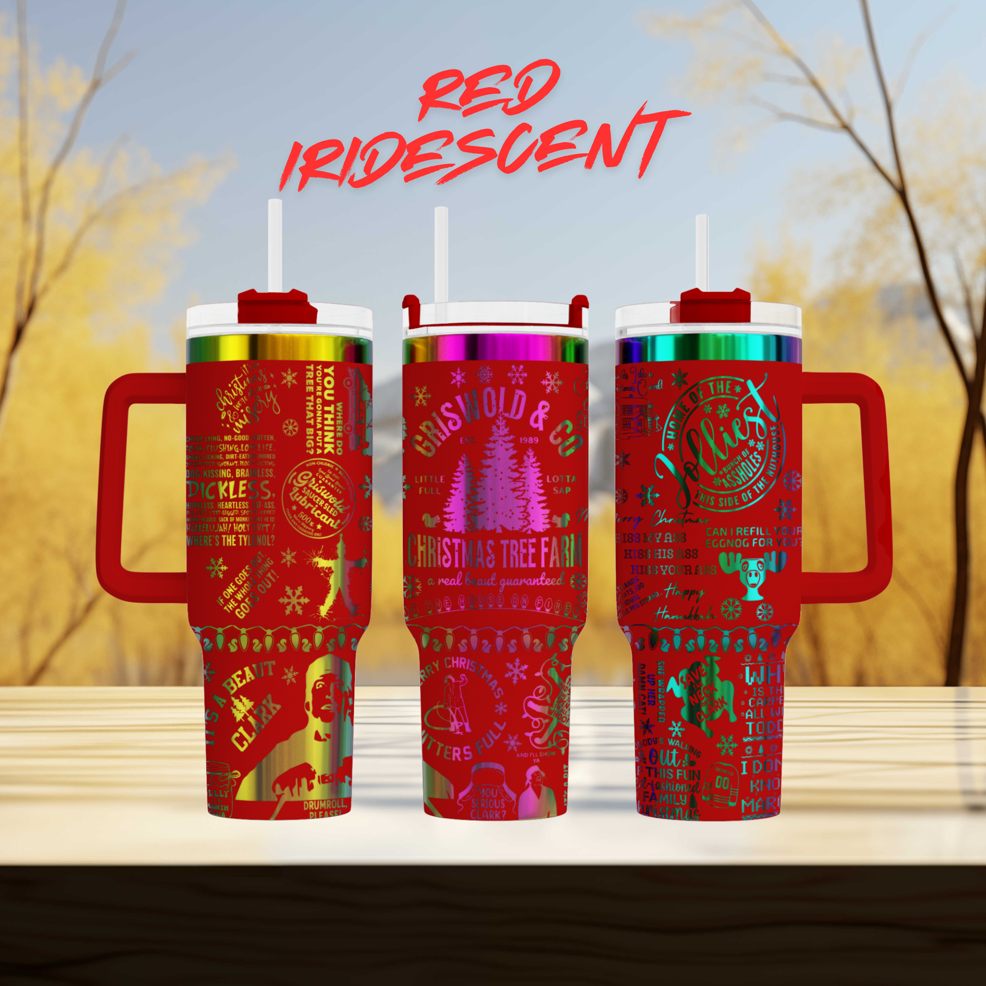 three red tumblers with handles, each adorned with various Christmas-themed designs and text. The background of the image is a blurred, natural setting with trees and a blue sky.