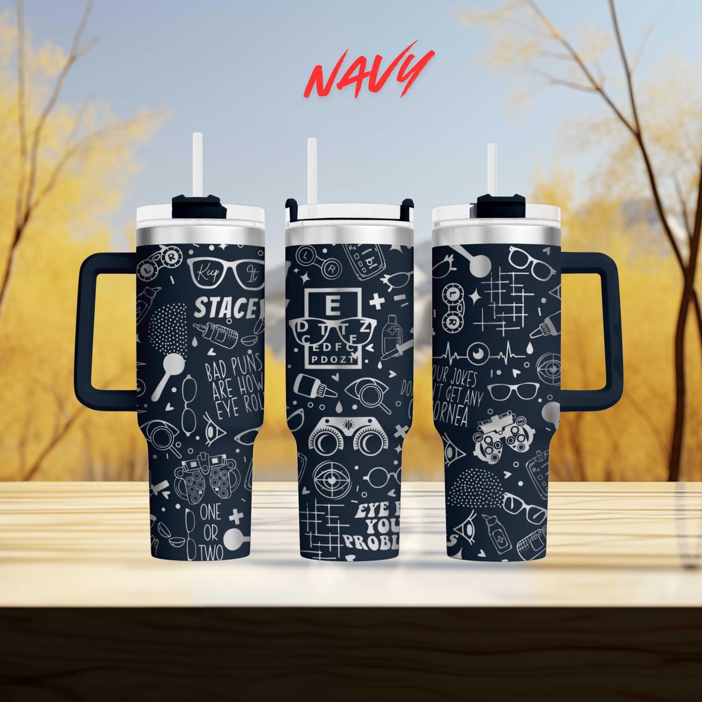 three black and white tumblers with various designs and text printed on them, placed on a wooden surface against a blurred background of trees.