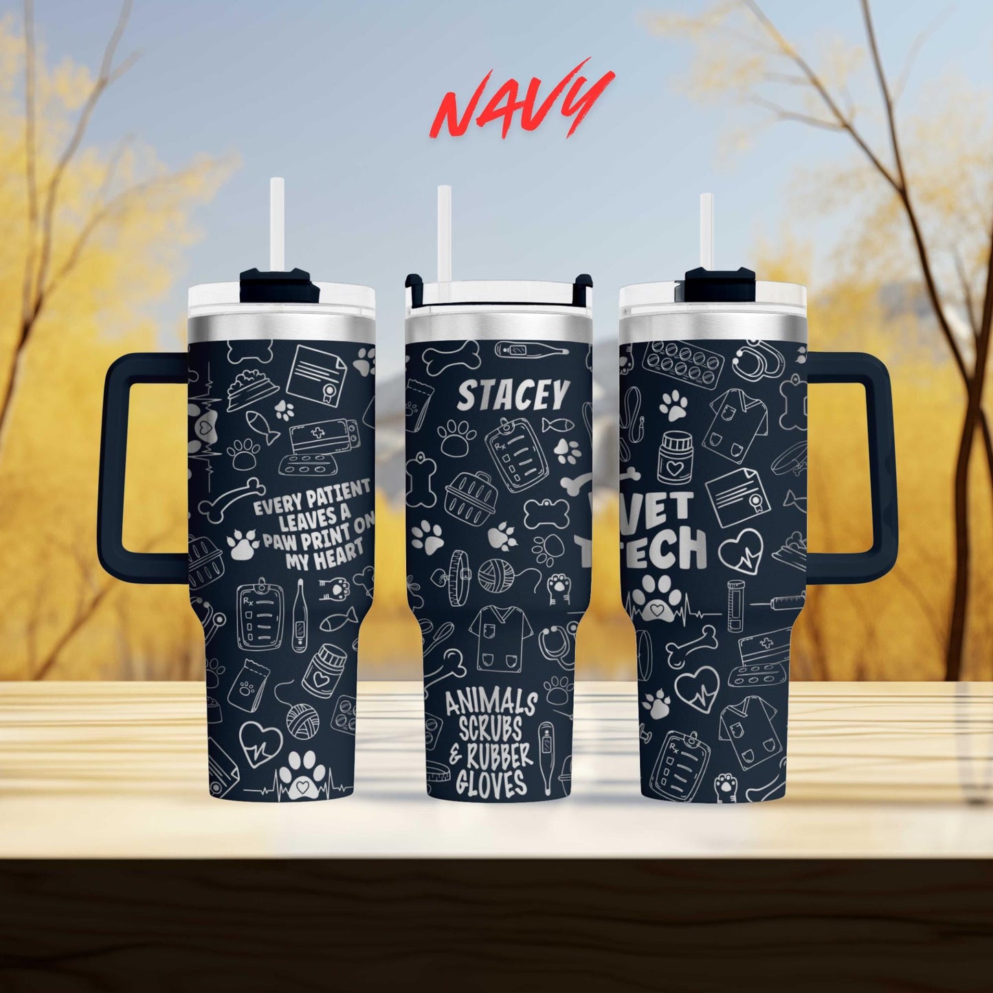 three black tumblers with white text and illustrations printed on them, set against a blurred background of trees.