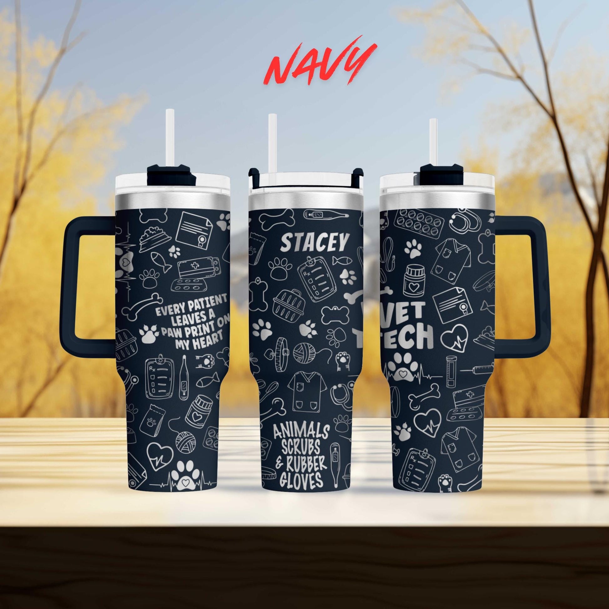 three black tumblers with white text and illustrations printed on them, set against a blurred background of trees.