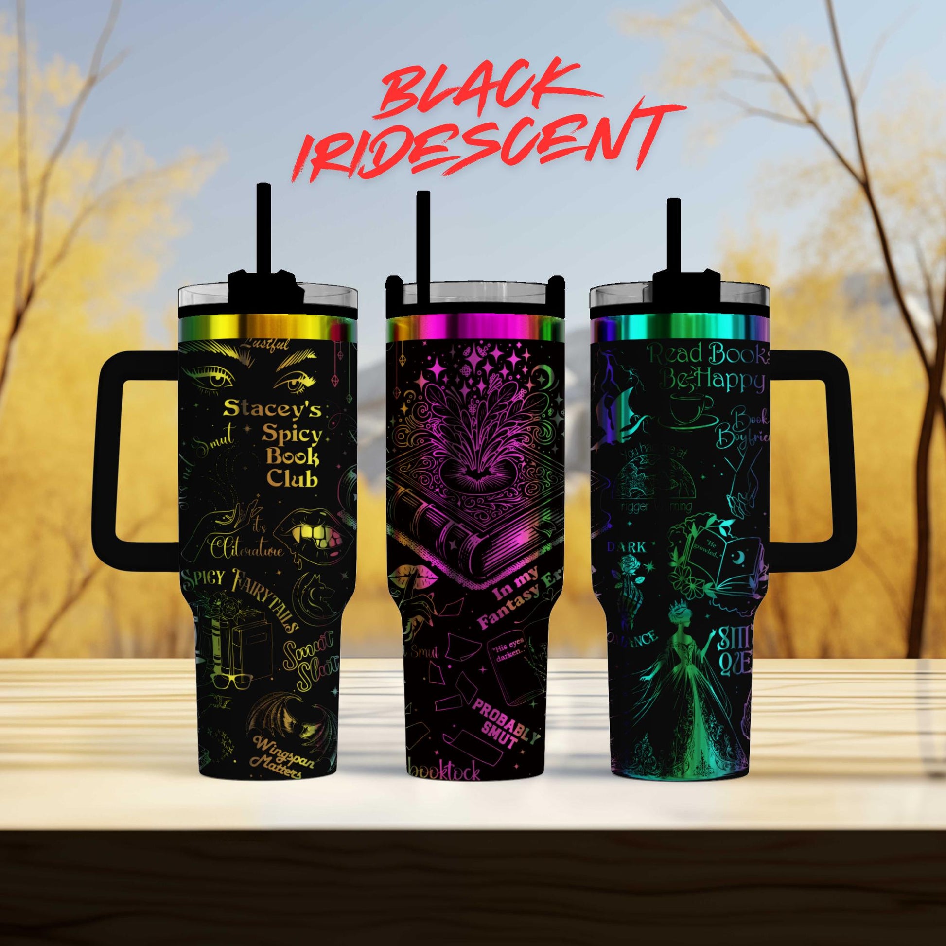 three colorful, patterned tumblers with handles, arranged on a wooden surface against a blurred background of trees.