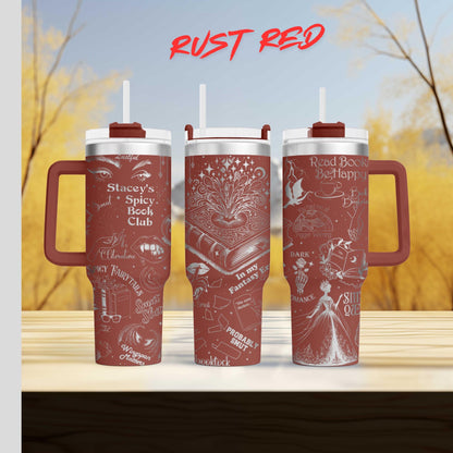 Three red tumblers with white text and illustrations on them, placed on a wooden surface against a blurred background of trees.