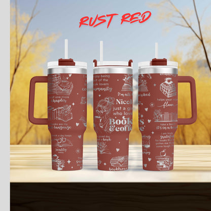 Three red tumblers with white text and illustrations on them, placed on a wooden surface against a blurred background of trees.