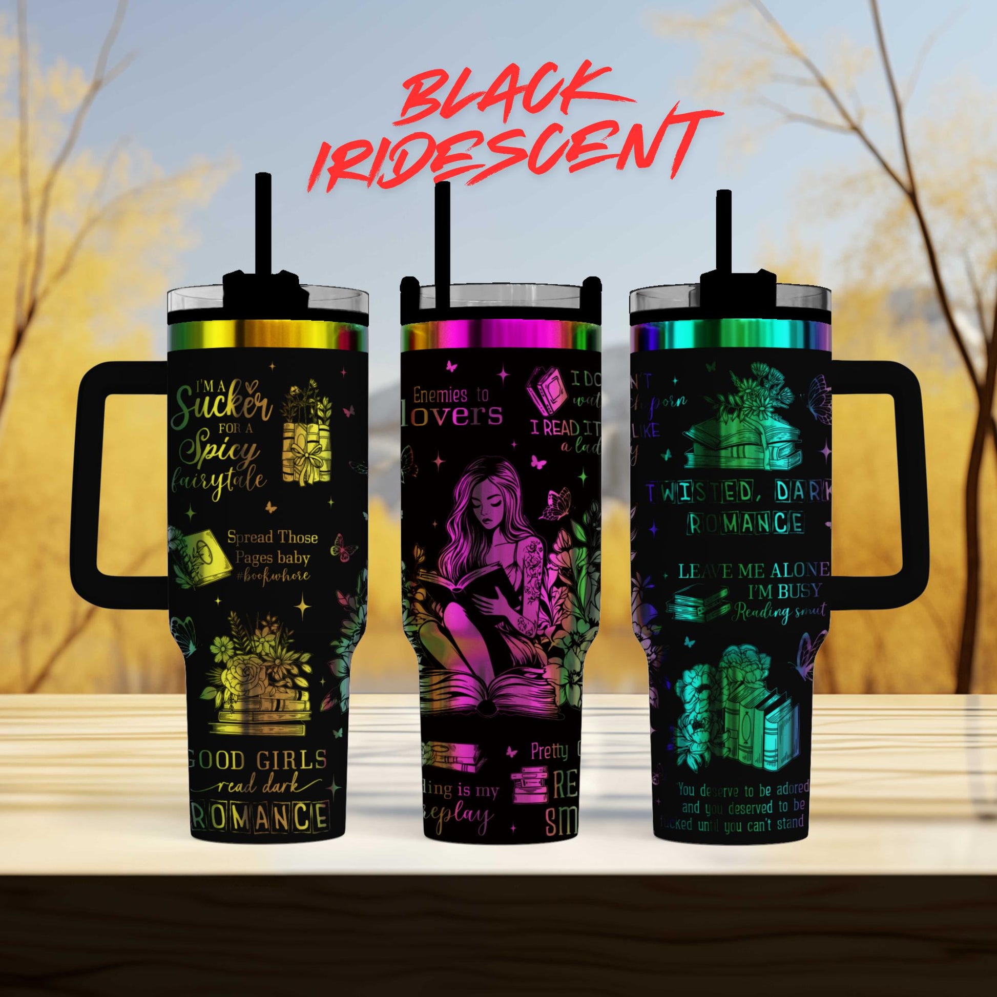 three colorful tumblers with various designs and text on them, placed on a wooden surface against a blurred background.