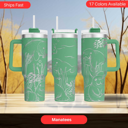 A set of three green tumblers with illustrations of manatees on them, displayed against a blurred background of trees.
