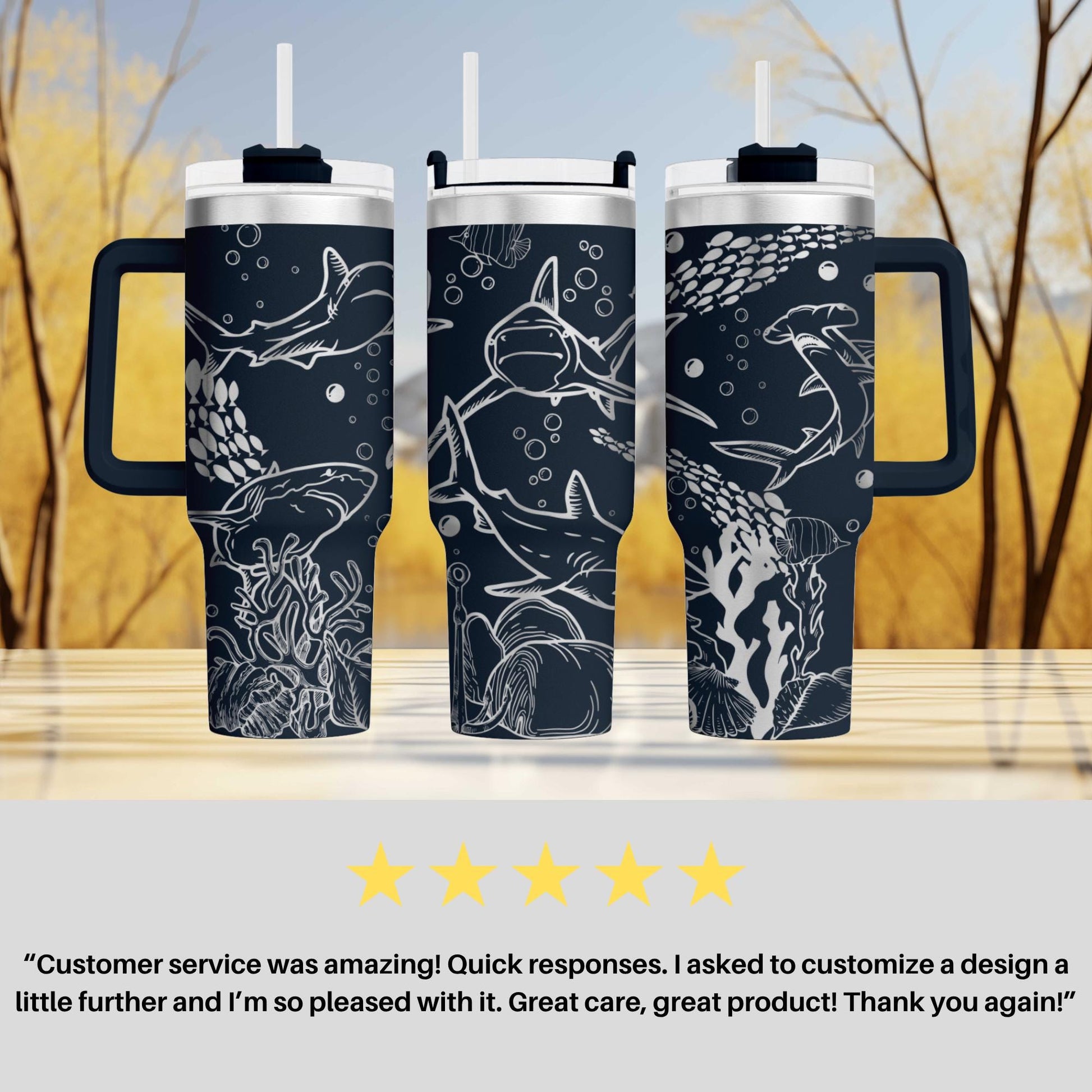 three black and white tumblers with shark designs, placed on a wooden surface against a blurred background of trees.