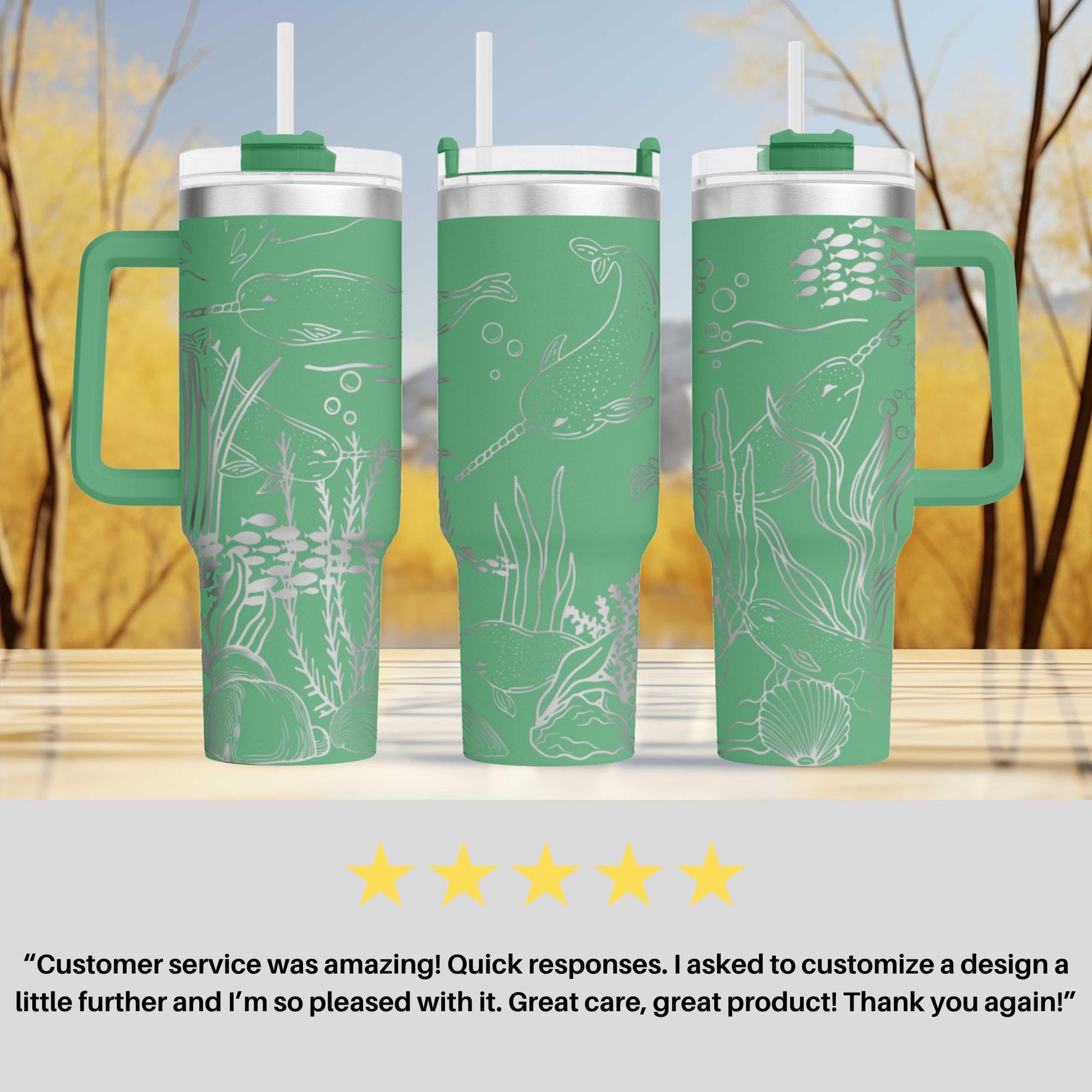 three green tumblers with white designs, including fish and seaweed, placed on a wooden surface against a blurred background of trees.