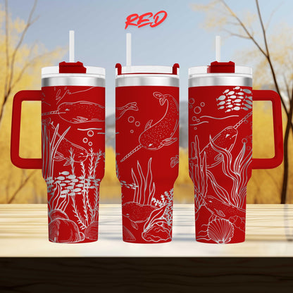 three red tumblers with white designs depicting marine life, including fish, plants, and bubbles, against a blurred background of trees.