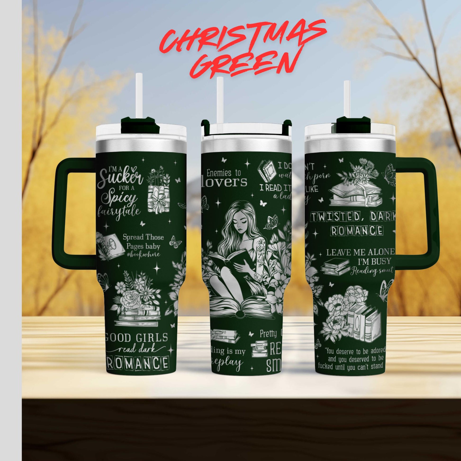 three green tumblers with white text and illustrations on them, set against a blurred background of trees and sky.