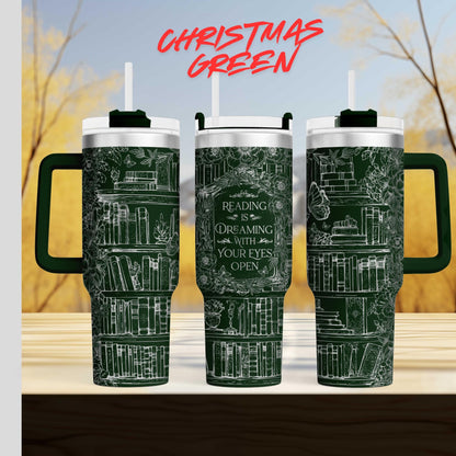 three green tumblers with white text and illustrations on them, set against a blurred background of trees and sky.