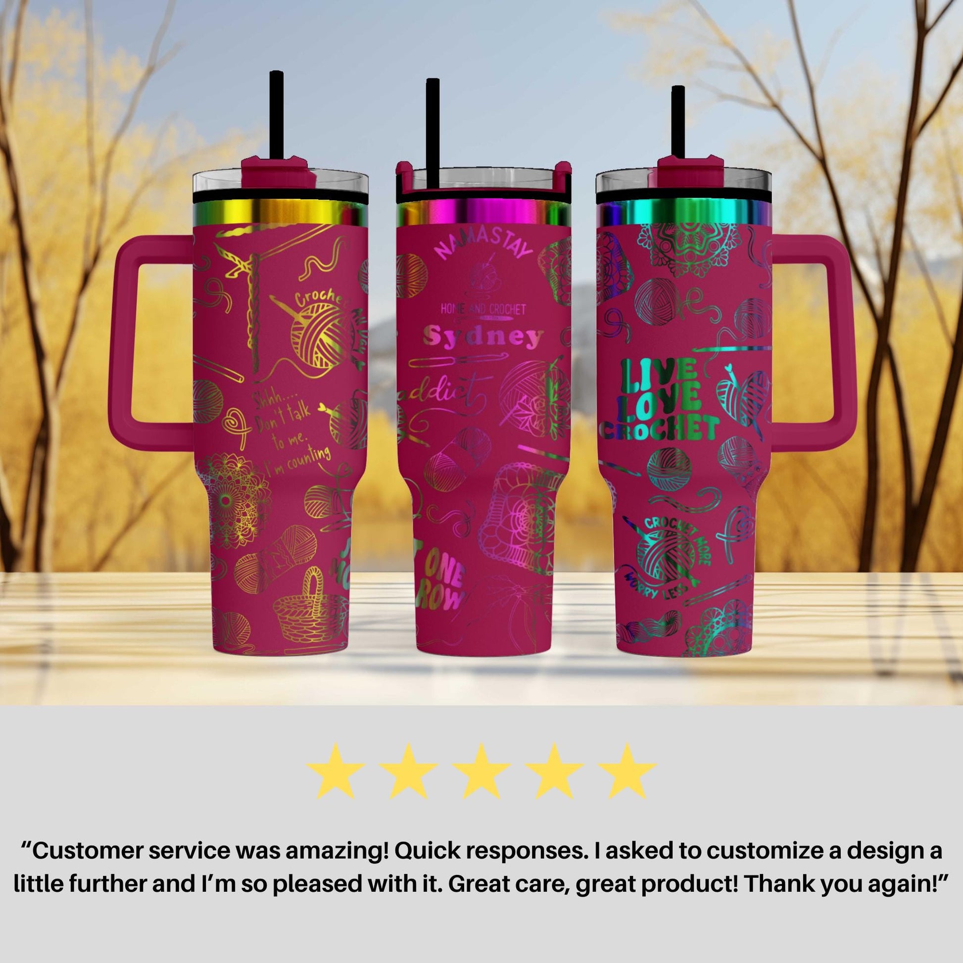three pink tumblers with colorful designs and straws, placed on a wooden surface against a blurred background of trees.