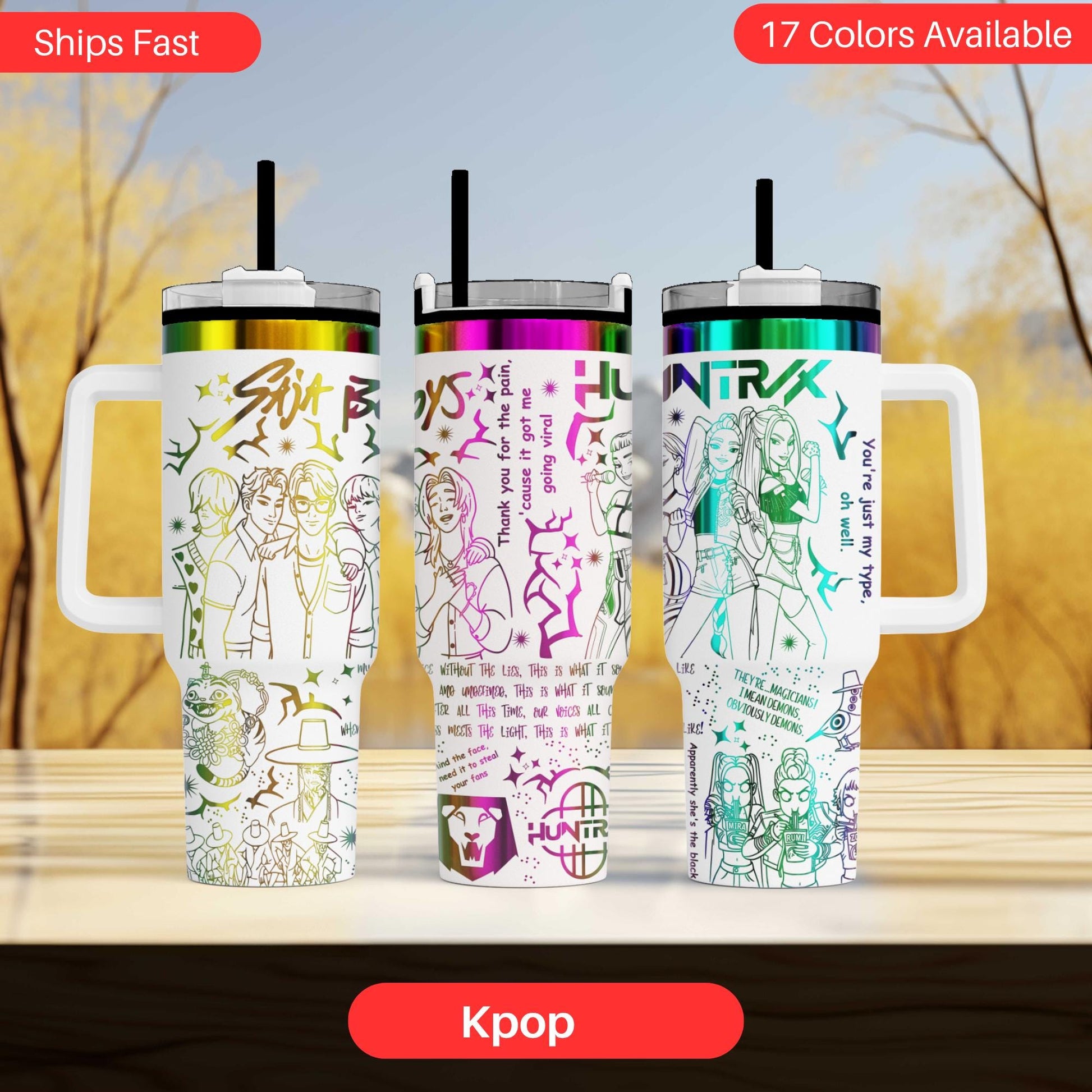 Three colorful tumblers with various designs and text, including Korean text, are displayed on a wooden surface against a blurred background.