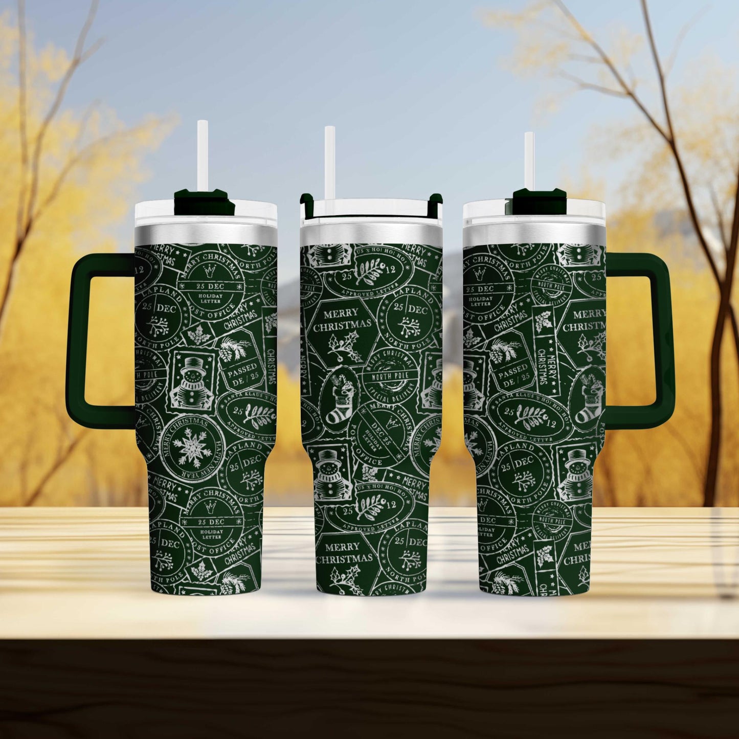 three green and white patterned travel mugs with handles, arranged on a wooden surface against a blurred background of trees.