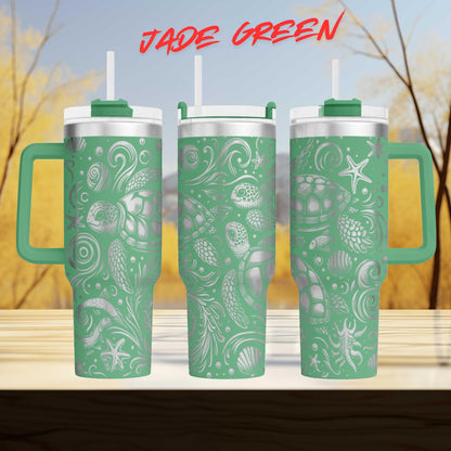 A set of three green tumblers with a pattern of sea creatures and plants on them, set against a blurred background of trees and sky.