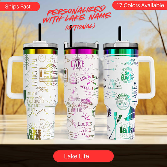 three colorful stainless steel tumblers with various lake-themed designs and text, including phrases like "Lakeside", "Life is Better at Lake", and "Lake Life". The tumblers are arranged in a row, with the middle one being the largest and the other two being smaller. The background of the image is a blurred outdoor scene with trees and a body of water.