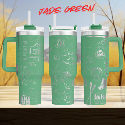 A set of three green tumblers with various text and illustrations printed on them, set against a blurred background of trees and a blue sky.