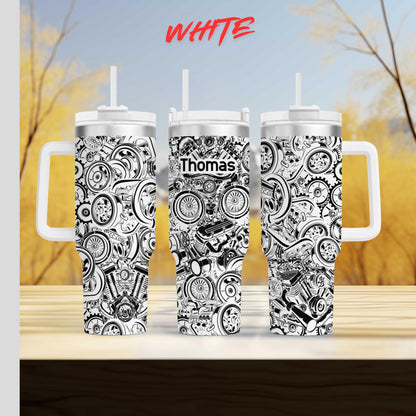 three black and white tumblers with the name "Thomas" printed on them. The tumblers are placed on a wooden surface against a blurred background of trees and foliage.